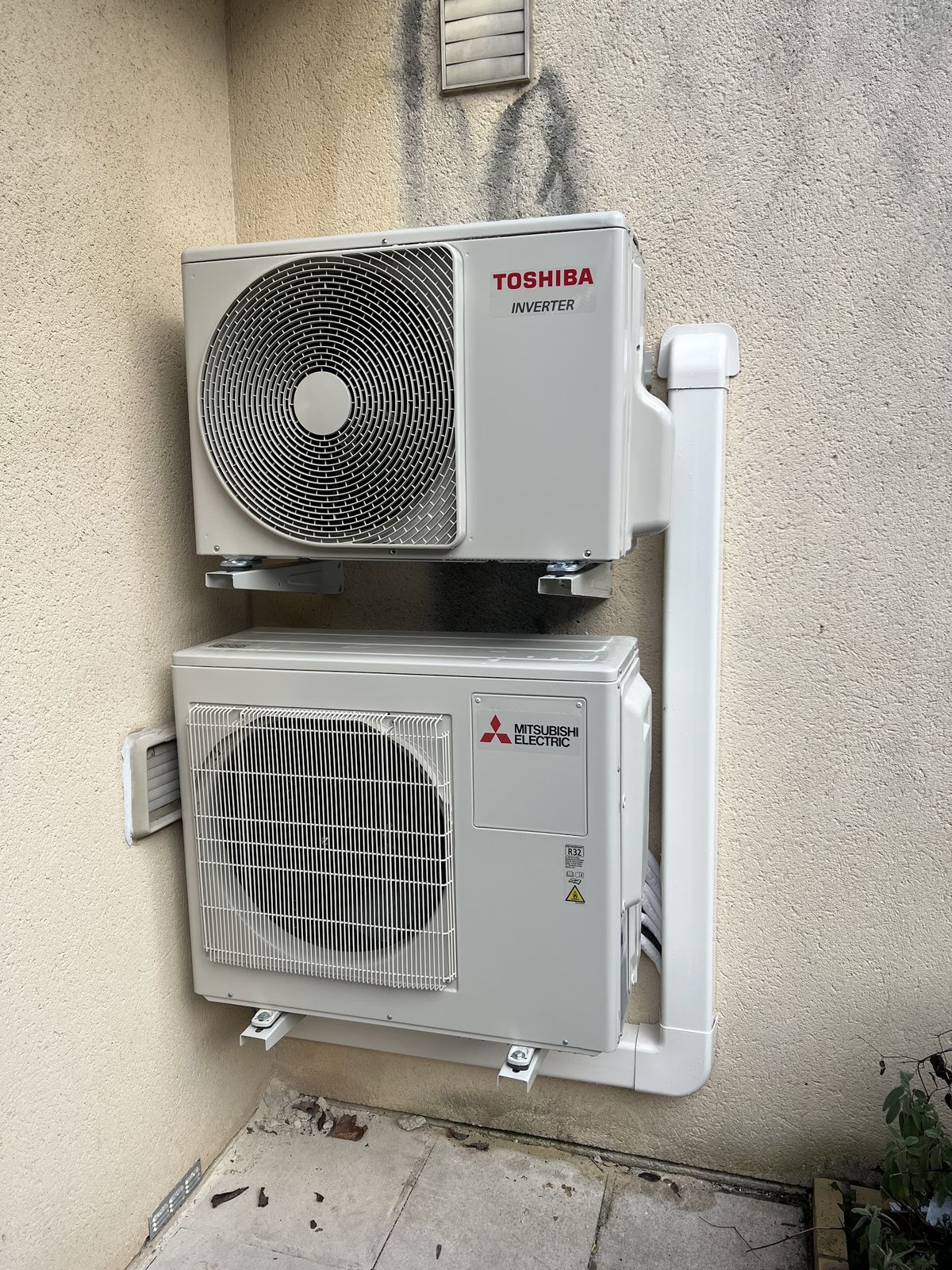 Deux groupes extérieurs, Toshiba et Mitsubishi Electric, fixés l'un au-dessus de l'autre en façade