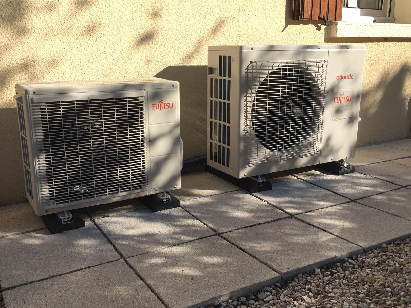 Deux groupes extérieurs Fujitsu posés sur des plots, sur une terrasse