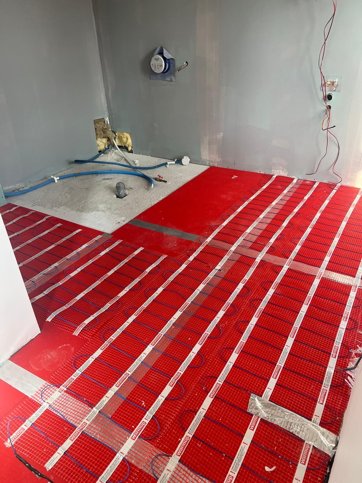 Plancher chauffant en cours de pose dans une salle d'eau : trames chauffantes avant le carrelage