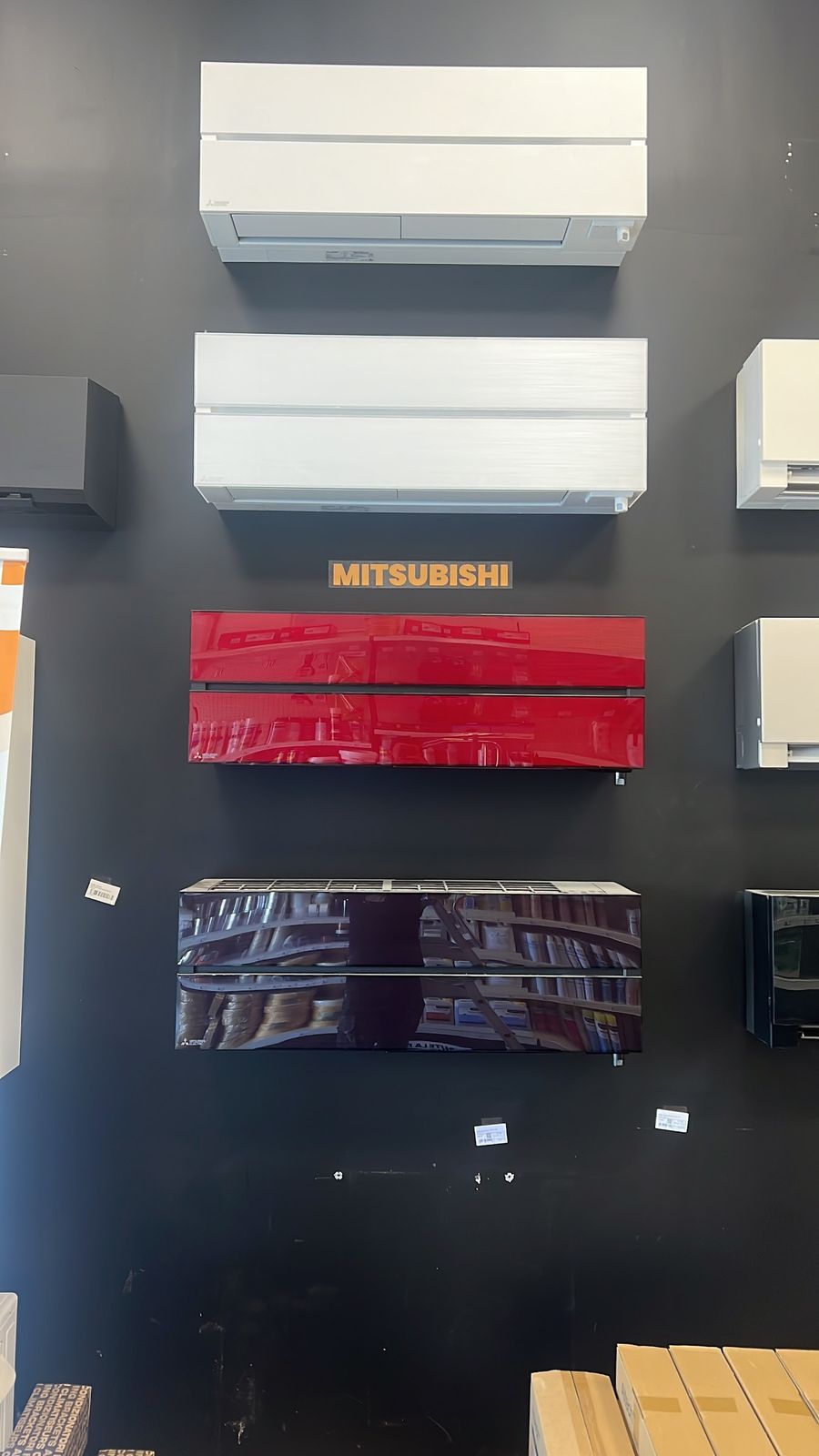 Unités murales Mitsubishi Electric, blanches, rouge et noire, sur un mur sombre